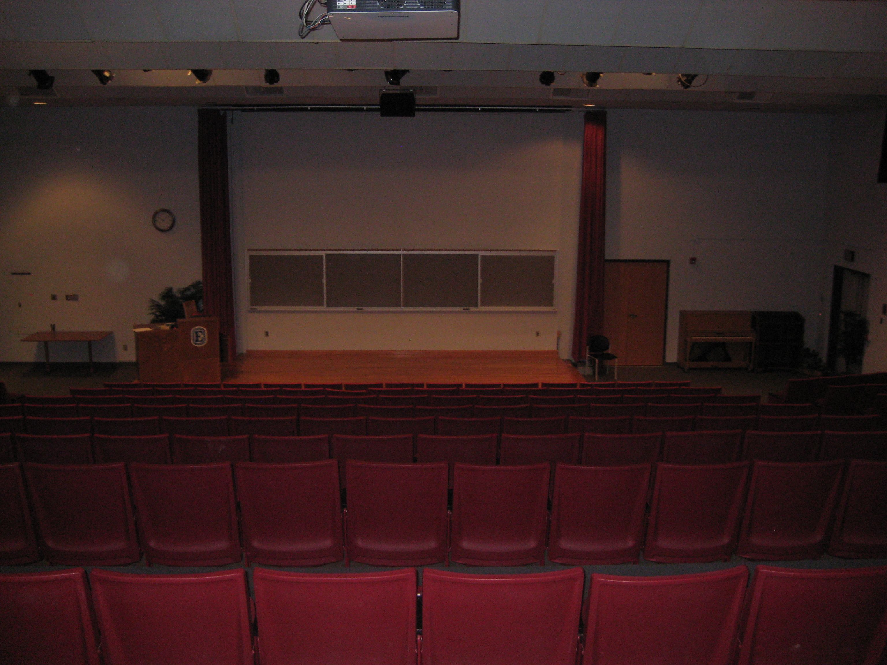 gibble auditorium looking down from top over seats to a stage with screen